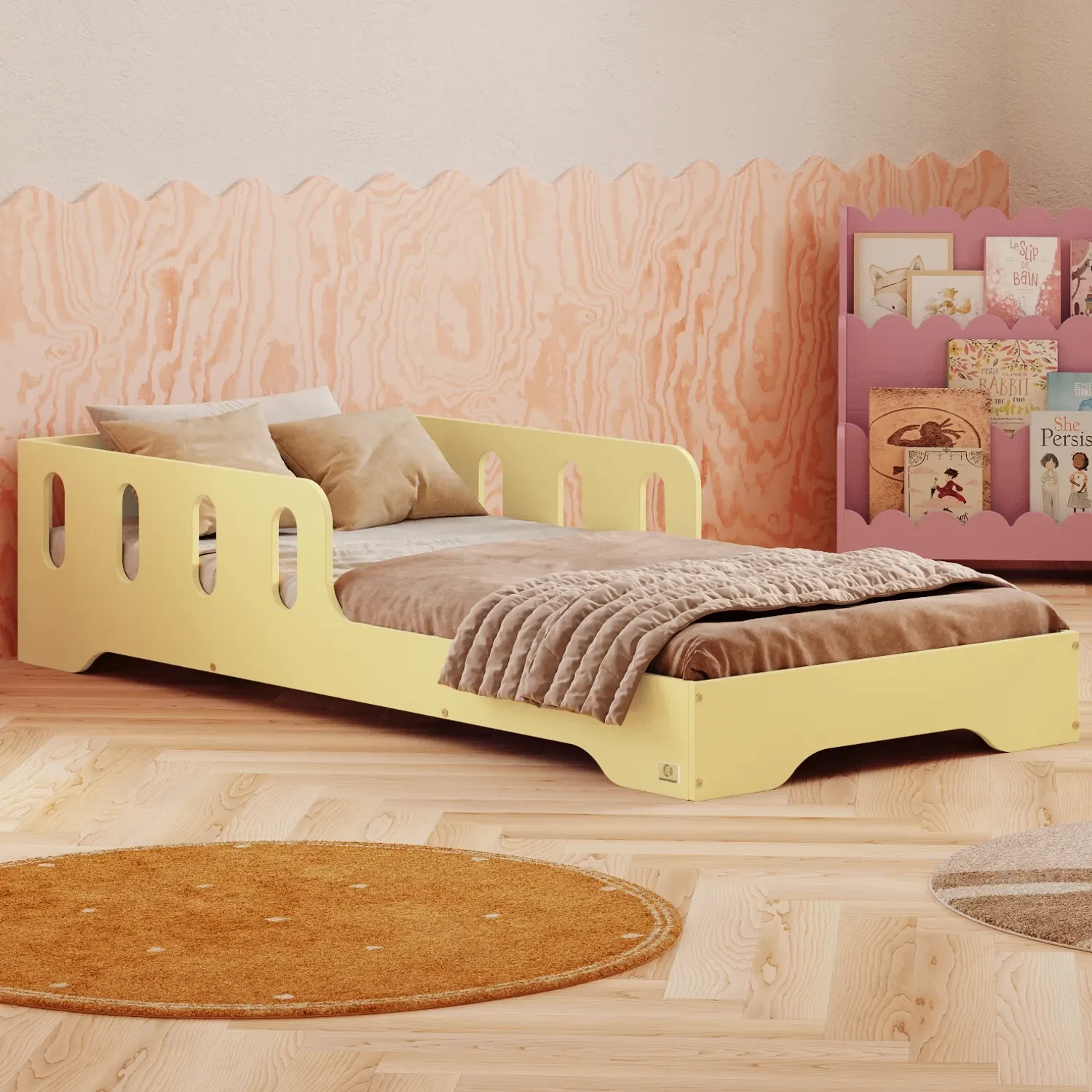 Buttergelbes Montessori-Kinderbett TILA 6 mit ausgesparten Öffnungen, gemütliche Tagesdecke und Bücherregal im hellen Kinderzimmer.